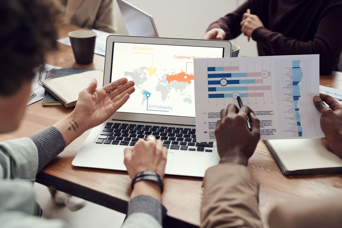 The image shows a group of people discussing visualized data. To ensure your charts and graphs are easy to interpret, following certain data visualization best practices can help.