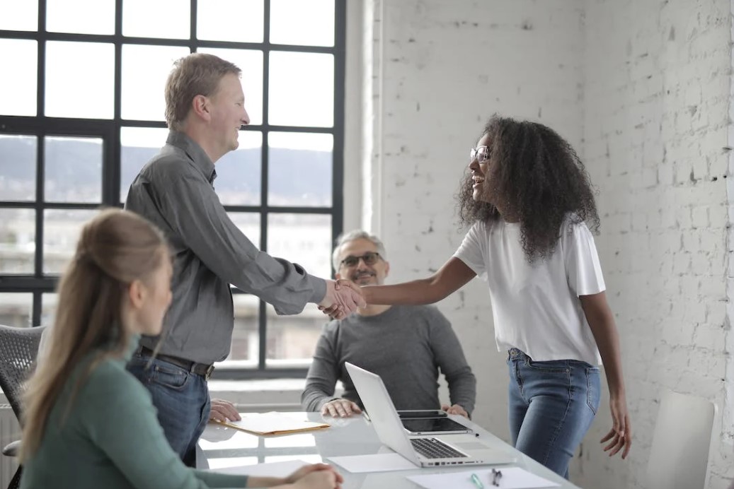 A company's in-house team shaking hands with their outsourced partners.